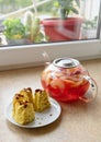 Slices of homemade cake on a plate and glass teapot with stewed fruits - apples, plums and strawberries on the windowsill, concept