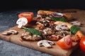Sliced Homemade Italian pizza with mushrooms ham tomatoes cheese onions and herbs on dark slate stone table Royalty Free Stock Photo