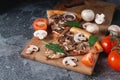 Slices of homemade Italian pizza on a chopping wooden board with mushrooms ham tomatoes cheese onions and herbs Royalty Free Stock Photo