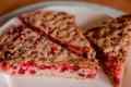 Slices of homemade sour berry pie on plate and whole tart cut in slices in baking dish on napkin on wooden table, view Royalty Free Stock Photo