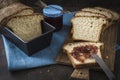 Slices of homemade white brad on a wooden slat, one spread with jam