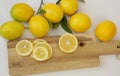 Slices of juicy lemons with leaves on a cutting wooden board and branches with lemon on a white background. Organic citrus fruits Royalty Free Stock Photo