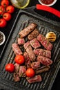 Slices of juicy steak with cherry tomatoes on grill pan. Royalty Free Stock Photo