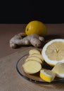 Slices of lemon and ginger lie on a plate on a brown background. Ingredients for making warming cold tea