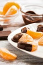 Slices of mandarin close-up in liquid chocolate served on a white plate. Selective focus.