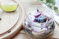 Slices of marinated mackerel with onion in a jar, lime, laurel and bread on wooden board