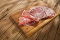 slices meat delicacy on a wooden surface close-up. dry-cured pork on a tray. traditional snack in rustic style.