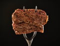 Slices of Medium rare grilled Steak Ribeye on meat fork on black background. Juicy piece of meat on a fork Royalty Free Stock Photo