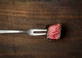 Slices of medium rare ribeye steak on meat fork on a dark wooden background Royalty Free Stock Photo