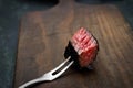 Slices of medium rare ribeye steak on meat fork on a dark wooden background Royalty Free Stock Photo