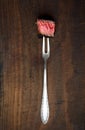 Slices of medium rare ribeye steak on meat fork on a dark wooden background Royalty Free Stock Photo