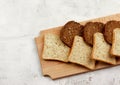 Slices of multigrain bread and rye bread on a wooden cutting board on a light gray background