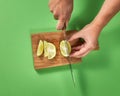 Slices of natural organic green lime, cutting by woman hands on a wooden cutting board on green. Royalty Free Stock Photo