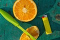 Slices of orange on green table, orange on green background, knife in a piece of orange, green knife, lighter and citrus slices on