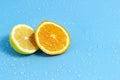 Slices of orange and lemon on a blue background with water drops. Summer cool water orange slices Royalty Free Stock Photo