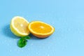 Slices of orange and lemon with mint leaves on a blue background with water drops. Summer cool water orange slices Royalty Free Stock Photo