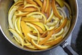 Slices of orange and lemon peels being cooked to make candied peels