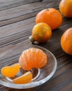 slices of orange and a ripe tangerine in glass saucer. Against the background the old wooden table. Royalty Free Stock Photo
