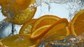 Slices orange splashing water in super slow motion close up. Citrus floating. Royalty Free Stock Photo