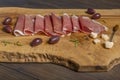 Slices of Parma ham placed on a rustic wooden cutting board with olives, parmesan flakes and rosemary leaves Royalty Free Stock Photo