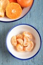 Slices of peeled tangerine in a bowl, top view. Close up of a mandarin orange over blue background. Royalty Free Stock Photo