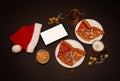 Slices of pepperoni pizza, ham pizza and chicken pizza, mugs of beer, tablet, Santa hat and jingle bells on dark background. Royalty Free Stock Photo