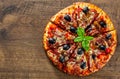 Pizza with Mozzarella cheese, salami, pepper, ham, pepperoni, olives, Spices and Fresh Basil. Italian pizza on wooden background Royalty Free Stock Photo