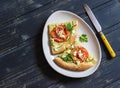 Slices pizza with zucchini, tomatoes, onions and feta cheese on a light ceramic plate on dark wooden background.