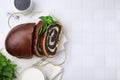 Slices of poppy seed roll served on white tiled table, flat lay with space for text. Tasty cake