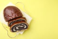 Slices of poppy seed roll on yellow background, top view with space for text. Tasty cake