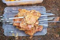 Slices of pork skewered on a skewers on container lid.