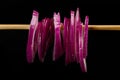 Slices of a purple onion hanging from a wooden stick