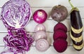 Slices of purple vegetables on wooden background - eggplant, beets, basil, onion, cabbage