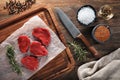 Slices of raw calf meat on white cooking paper and wooden cutting table