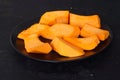 Slices of raw pumpkin with orange-yellow flesh in stainless steel bowl on a black background Royalty Free Stock Photo