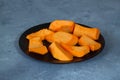 Slices of raw pumpkin with orange-yellow flesh in stainless steel bowl on a stone background Royalty Free Stock Photo