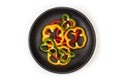Slices of red, green and yellow peppers on a black plate Royalty Free Stock Photo
