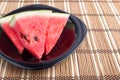 Slices of red watermelon on a black plate on a bamboo mat Royalty Free Stock Photo