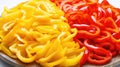 Slices of red and yellow bell pepper on a wooden plate. Closeup view. Sliced pepper background