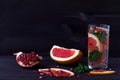 Slices of ripe grapefruit and pomegranate on black background with glass of red cocktail. detox water. diet healthy eating and wei Royalty Free Stock Photo