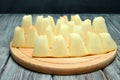 Slices of ripe melon, cut into small pieces on the peel, lie on a cutting board. The board lies on a rough wooden table Royalty Free Stock Photo