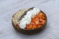 Slices of sweet papaya with oat flakes, chia seeds and white yogurt in coconut bowl on white wooden background, close up Royalty Free Stock Photo