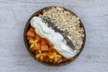 Slices of sweet papaya with oat flakes, chia seeds and white yogurt in coconut bowl on white wooden background, close up Royalty Free Stock Photo