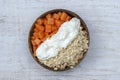 Slices of sweet papaya with oat flakes and white yogurt in coconut bowl on white wooden background, close up Royalty Free Stock Photo