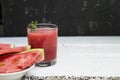 Slices of ripe watermelon on a plate and red watermelon juice in a glass on a wooden white background, and a black wall - side Royalty Free Stock Photo