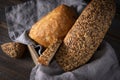 Rye grain bread in a basket with a napkin on a dark wooden background, wheat loaf, ciabatta, close-up, top view