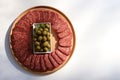 Slices of salami pepperoni and green pickled olives on round wooden cut board on white background. Top view Royalty Free Stock Photo