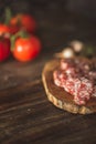 Slices of salami with tomatoes on a cutting board on a wooden table. Selective focus
