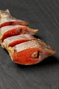 Slices of salted air-dried roach with roe on black wooden table