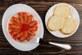 Slices of salted pink salmon in jar on plate, fork, pieces of bread in plate on wooden table. Top view